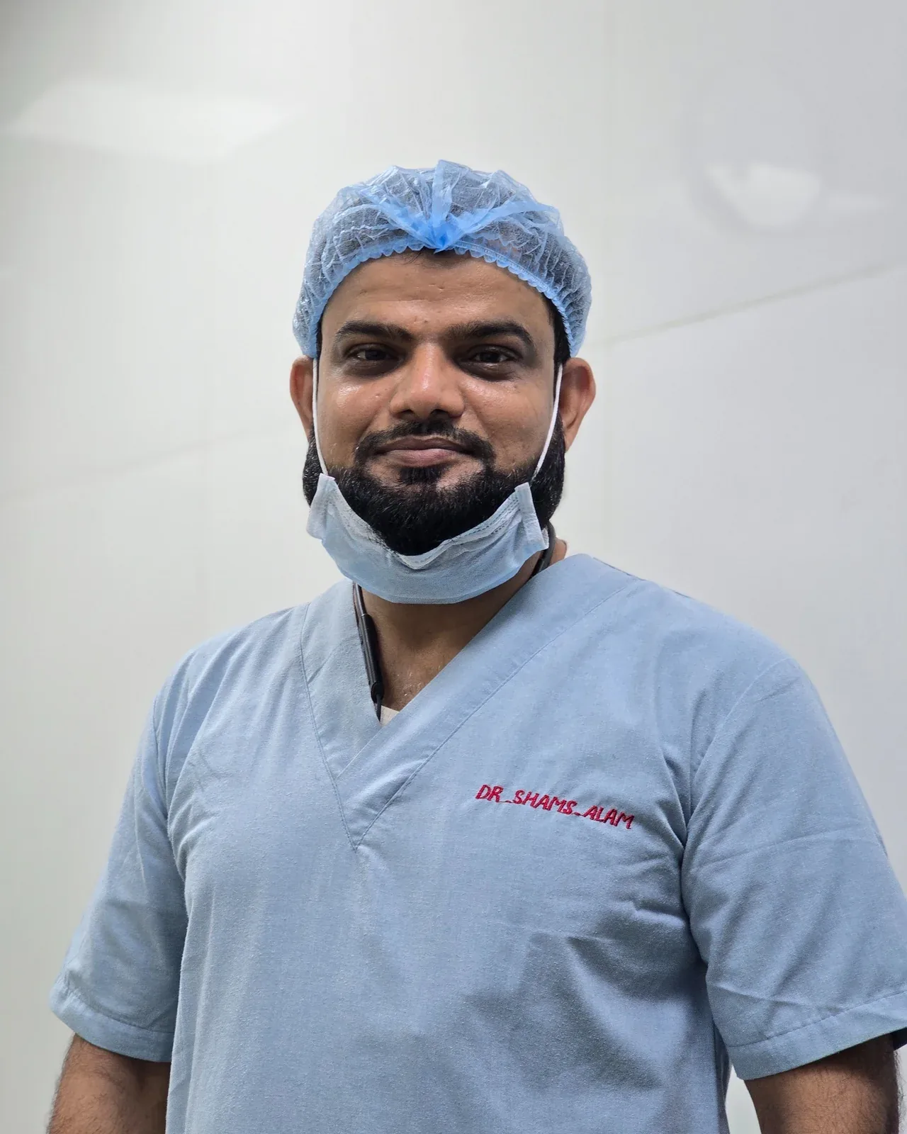 Dr. Shams Alam wearing surgical scrubs and a surgical cap